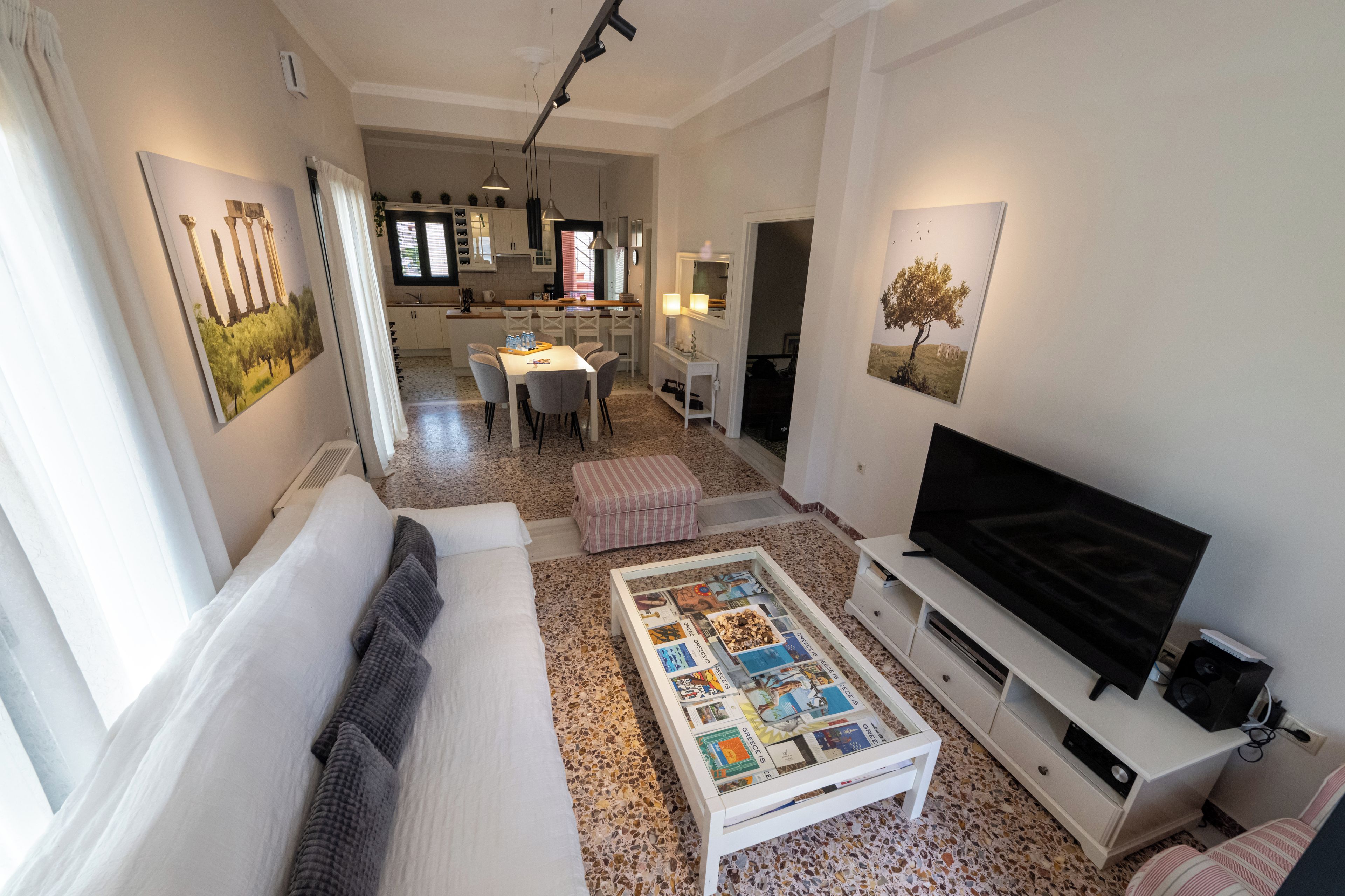 Un soggiorno con divano, tavolino, televisione e opere d'arte alle pareti.