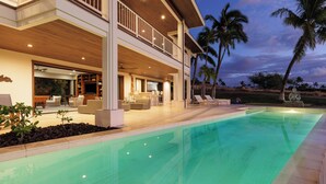 A modern house with a swimming pool, a covered outdoor seating area, and a view of palm trees. - Beautiful Mauna Kea Home, Ocean and Sunset Views (Kamuela)