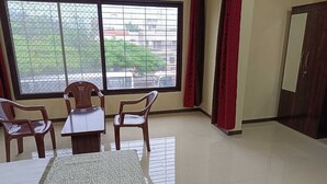 Ein Zimmer mit großem Fenster, einem Tisch, zwei Stühlen und einem Bett.
