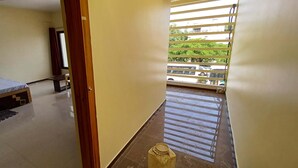Ein Schlafzimmer mit einem Bett, einem Schreibtisch und einem Fenster mit Blick auf die Straße.
