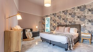 Een moderne slaapkamer met een groot bed, een houten dressoir, een bureau en een vloerlamp.