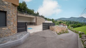 Un bâtiment en pierre doté d’une entrée fermée par un portail, d’une rampe d’accès pour les personnes à mobilité réduite et offrant une vue sur un paysage montagneux.