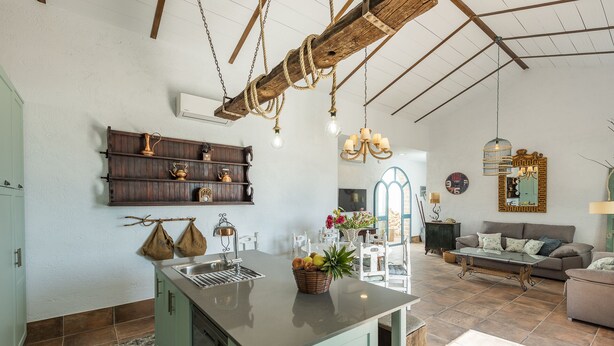 A spacious kitchen with a central island, wooden shelves, and a rustic ceiling. - Villa Colona, Los Algarbes J22g+94 (Los Algarbes- La Carlota)