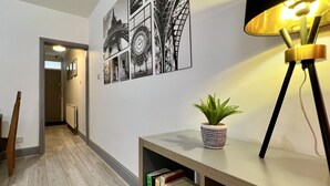 Passadís amb una biblioteca, una planta en testos i decoració mural que inclou la Torre Eiffel.