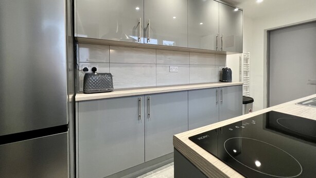 Una cuina moderna amb electrodomèstics d'acer inoxidable, un forn de mur i una superfície amb una tetera.