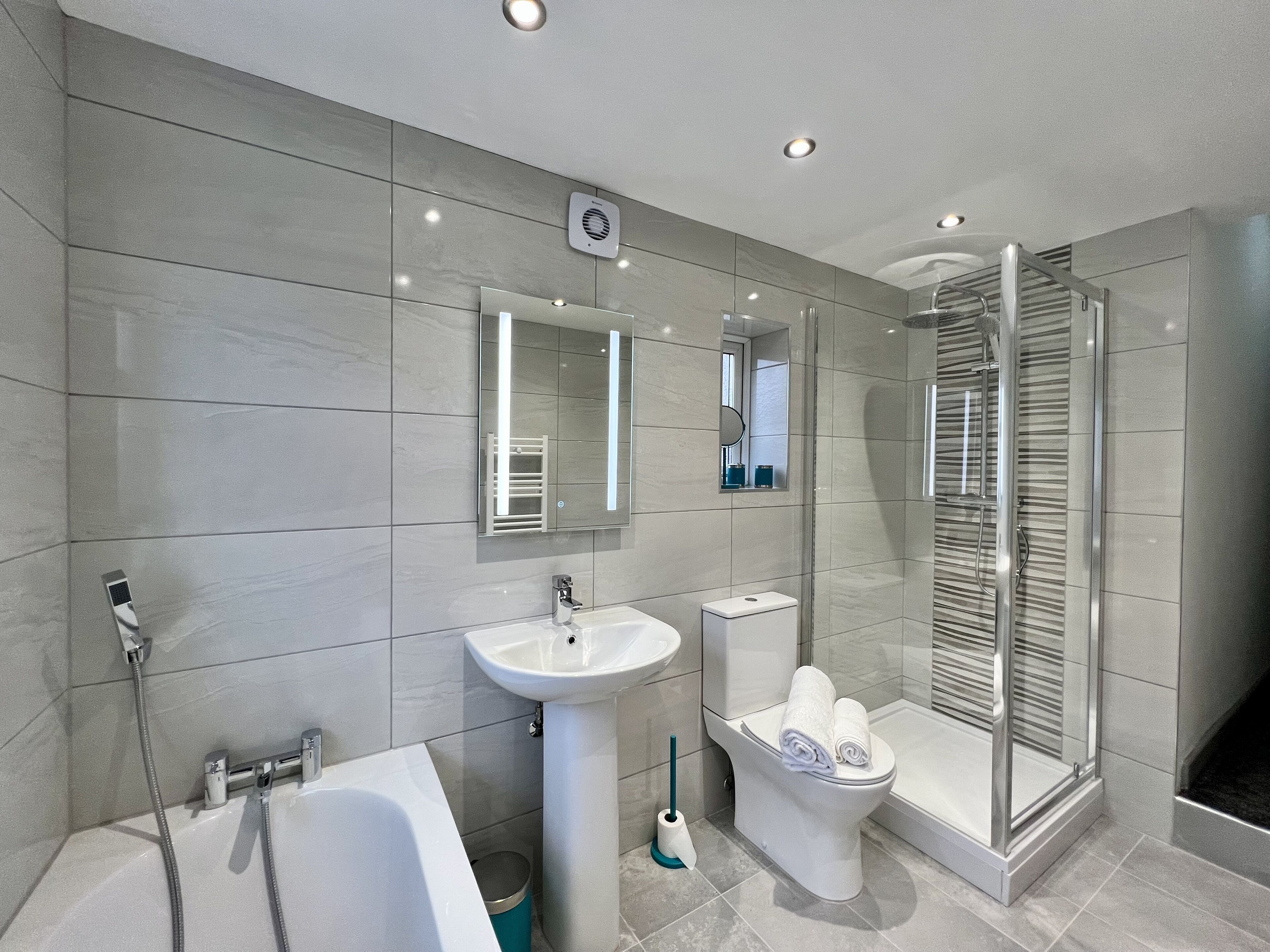 Un bagno moderno con vasca, lavandino, water e doccia a parete in vetro.