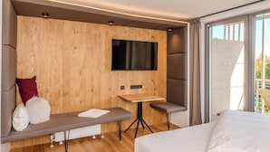 Une chambre d’hôtel moderne avec un mur d’accent en bois, un téléviseur à écran plat, une petite table en bois, un banc et un lit.
