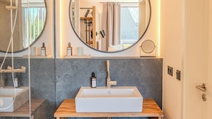 Une salle de bain moderne avec un grand miroir, un lavabo et une douche.