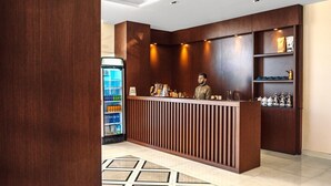 A reception area with a wooden counter, a refrigerator stocked with beverages, and shelves with decorative items. - Suknai Salah ElDin Serviced apartments (Ha'il)