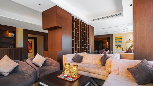 A modern lobby with a sofa set, a coffee table with decorative items, and a wooden partition. - Suknai Salah ElDin Serviced apartments (Ha'il)