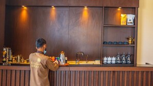 A bar area with a wooden counter, coffee-making equipment, and tea sets. - Suknai Salah ElDin Serviced apartments (Ha'il)