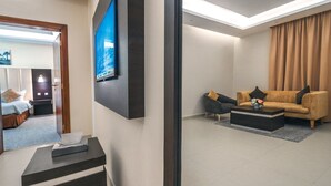 A modern hotel room with a flat-screen TV mounted on the wall, a sofa set, a coffee table, and a small table with a tissue box. - Suknai Salah ElDin Serviced apartments (Ha'il)