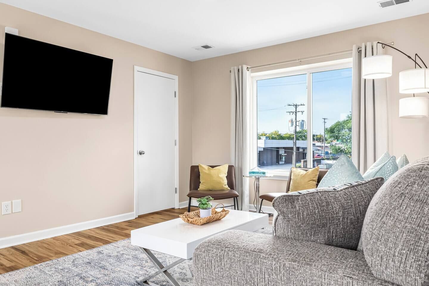 Ein modernes Wohnzimmer mit Flachbildfernseher, Sofa, Couchtisch und Blick ins Freie.