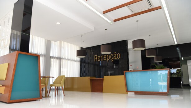 Uma área de recepção moderna com parede preta, sinalização dourada e balcão azul.