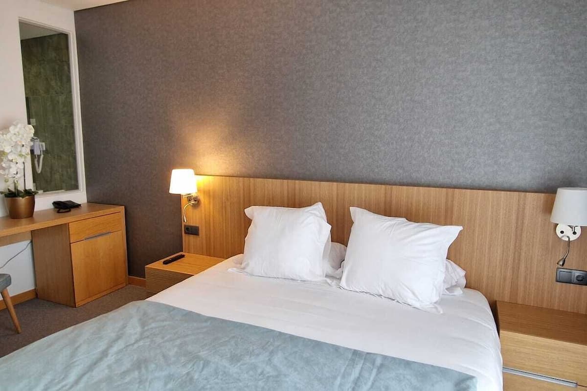 Ein Hotelzimmer mit Bett, Nachttischen, Schreibtisch, Stuhl und Lampe.