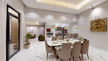 A modern dining area with a marble floor, a round table set for six, and pendant lighting.