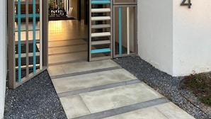 A modern building entrance with a metal gate, a concrete pathway, and a number '4' on the wall. - Ayla Vacation home 
 (Aqaba)