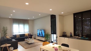 A modern living room with a sofa, TV, dining table, and chairs. - Ayla Vacation home 
 (Aqaba)