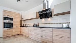 Una cocina moderna con armarios de madera, horno integrado y campana de acero inoxidable.