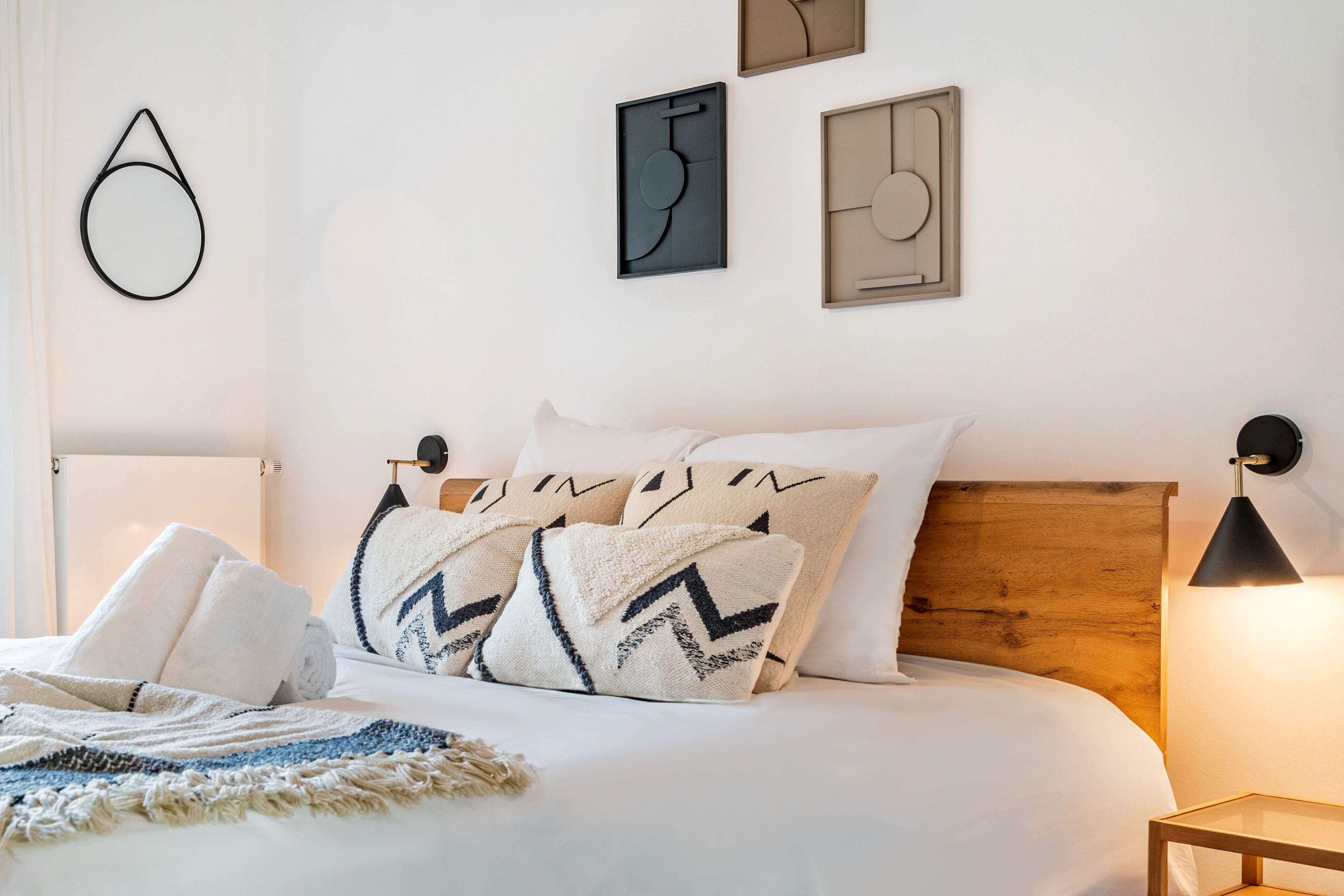 Ein ordentlich bezogenes Bett mit Kissen, einer Tagesdecke und einem Nachttisch mit Lampe.