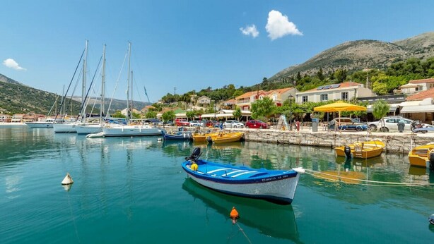 Un port de plaisance avec des bateaux amarrés, un ciel dégagé et des bâtiments en arrière-plan.