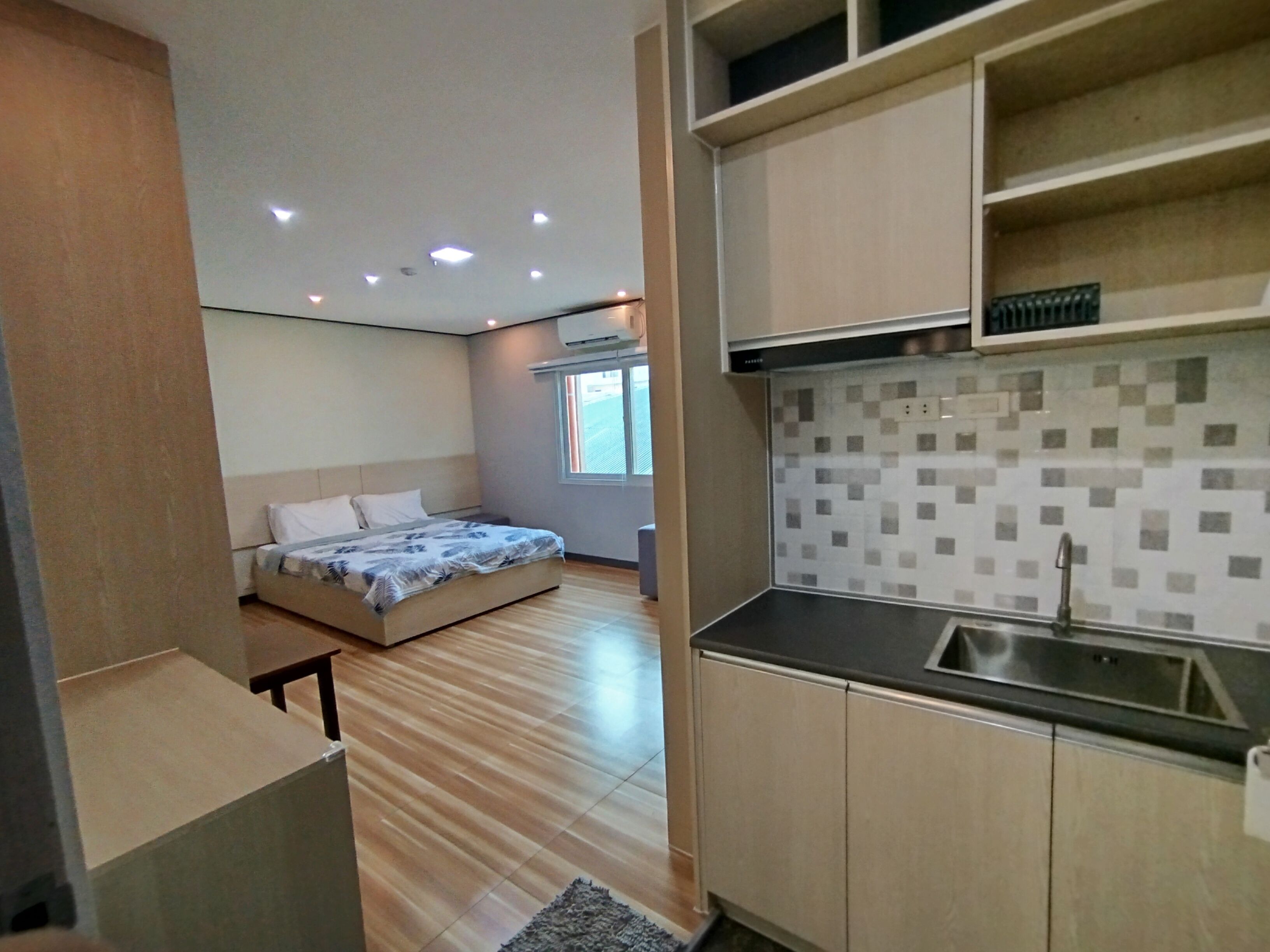 Quarto de hotel compacto com cama, cozinha compacta e banheiro pequeno.