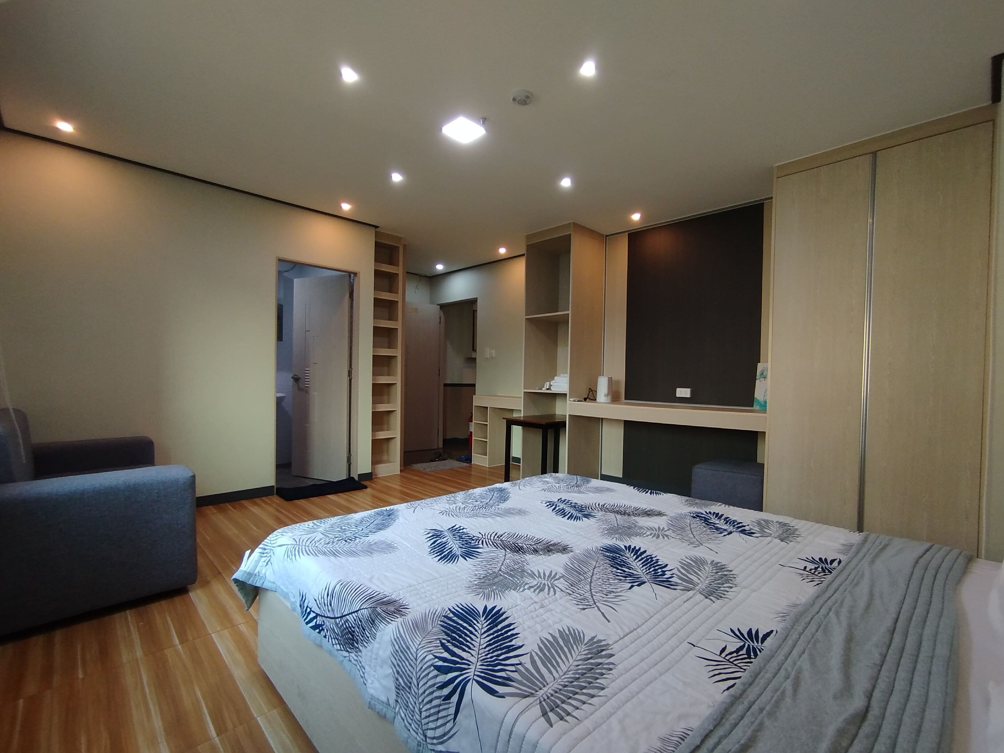 Een moderne slaapkamer met een groot bed, een inbouwkast en een zithoek.