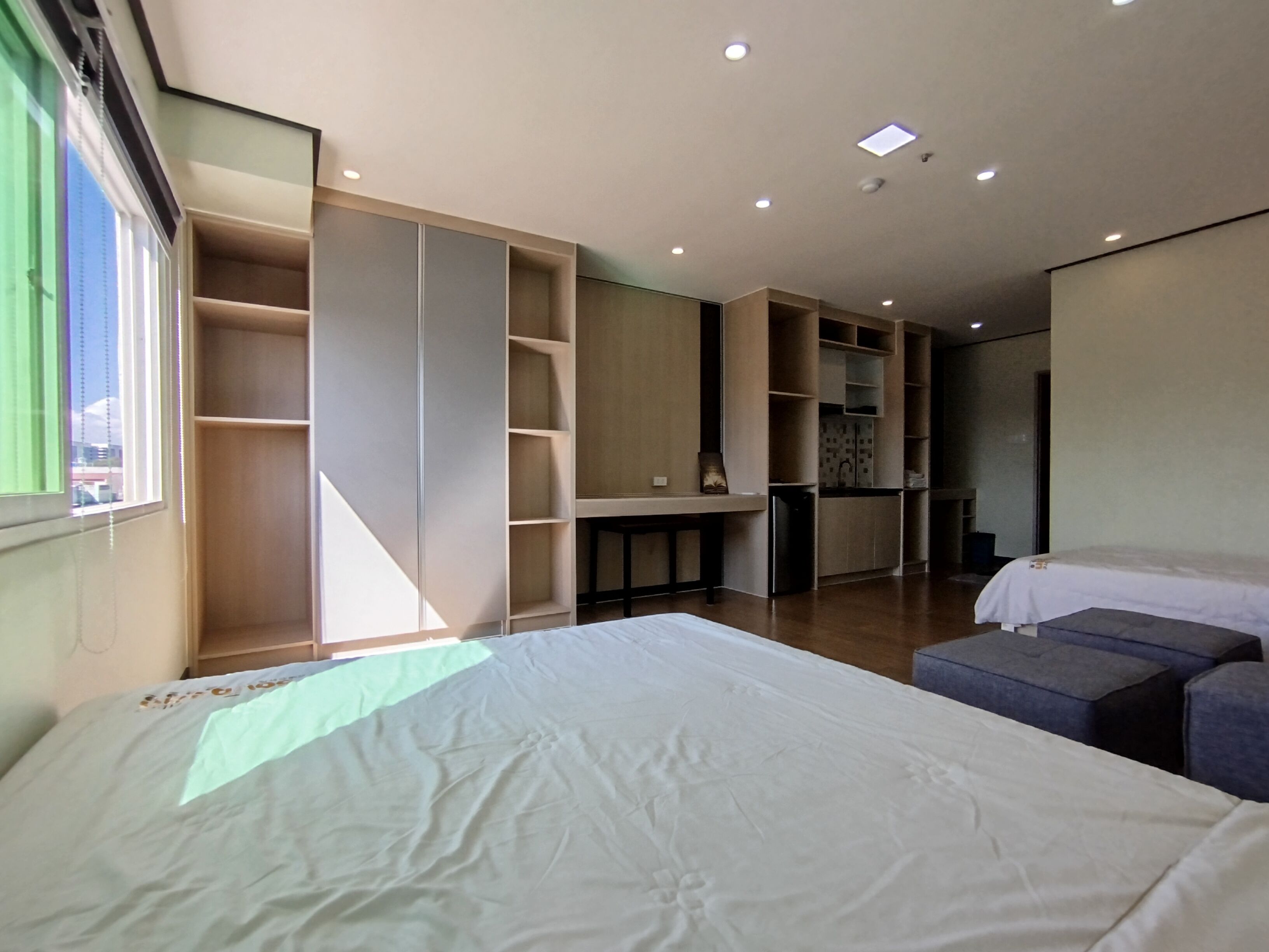 A modern bedroom with a large bed, a desk, and built-in shelving.