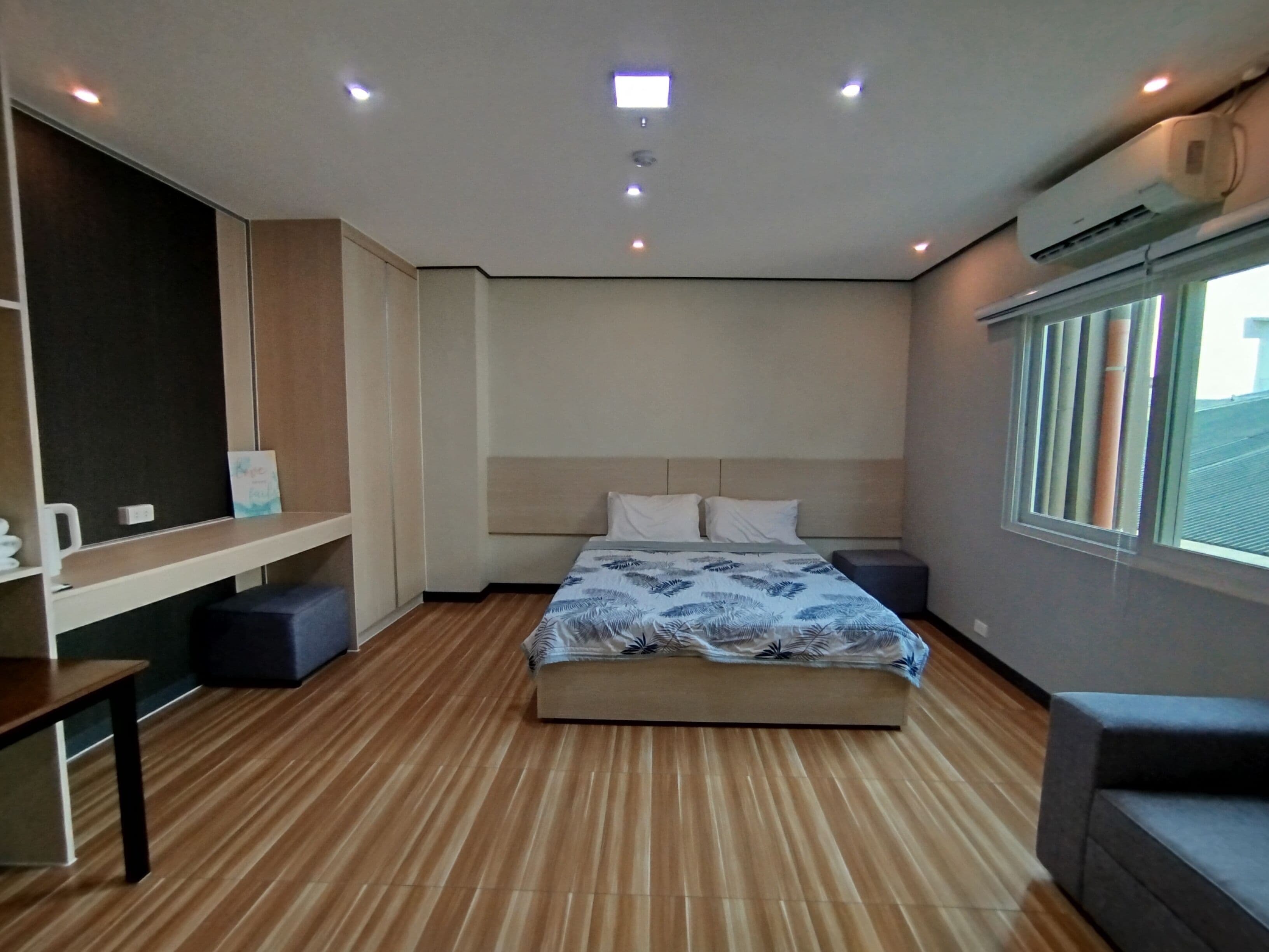 Et moderne hotelværelse med seng, sengebord og et stort vindue.