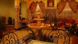 A Moroccan-themed room with a fountain, patterned walls, and traditional furniture. - Riad Mahjouba Marrakech & SPA (Marrakech)