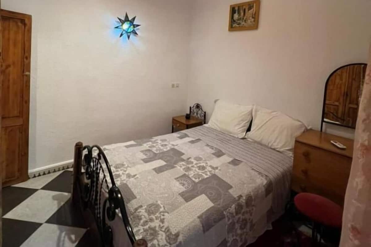A bedroom with a bed, a nightstand, a dresser, a star-shaped light, and a checkered floor.