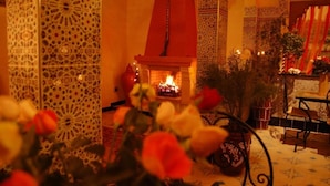 A traditional Moroccan interior with intricate tile work, a central fireplace, and a seating area with a patterned rug. - Riad Mahjouba Marrakech & SPA (Marrakech)