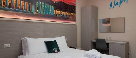 A hotel room with a bed, a desk, a chair, and a large painting of a cityscape.