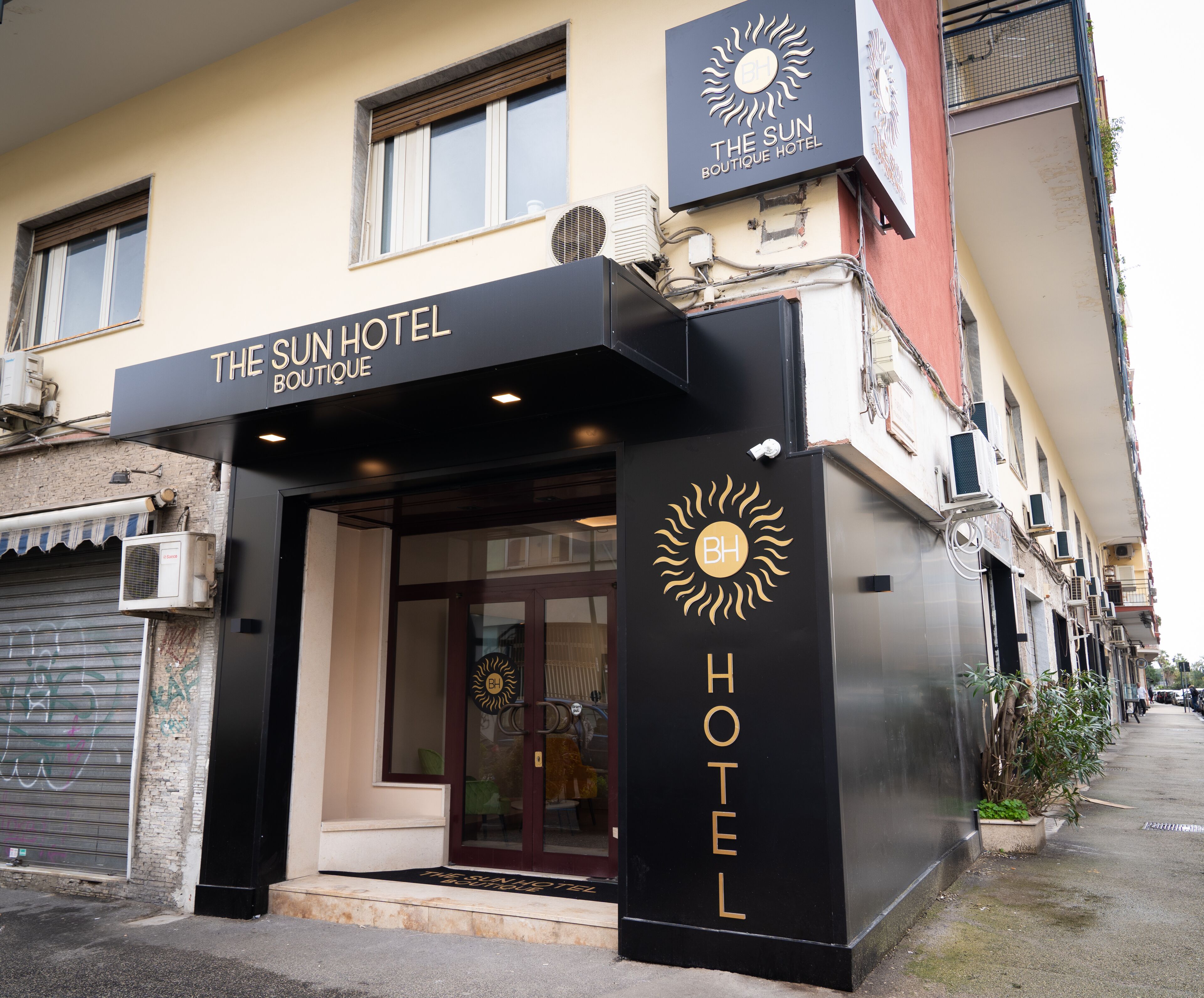 A hotel entrance with a sign reading "The Sun Hotel Boutique Hotel".