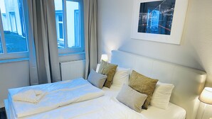 Ein Hotelzimmer mit einem großen Bett, einem Nachttisch mit Lampe und einem gerahmten Bild an der Wand.