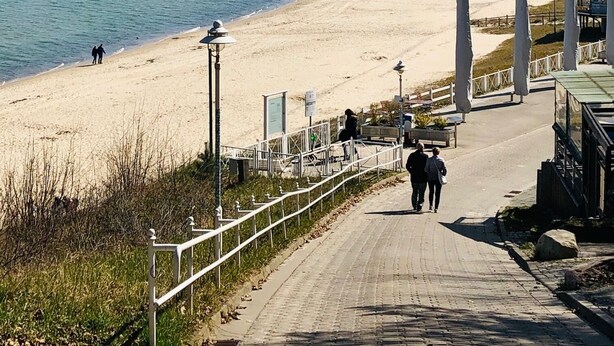 Ein Küstenweg, der zu einem Sandstrand mit freiem Blick auf das Meer führt.