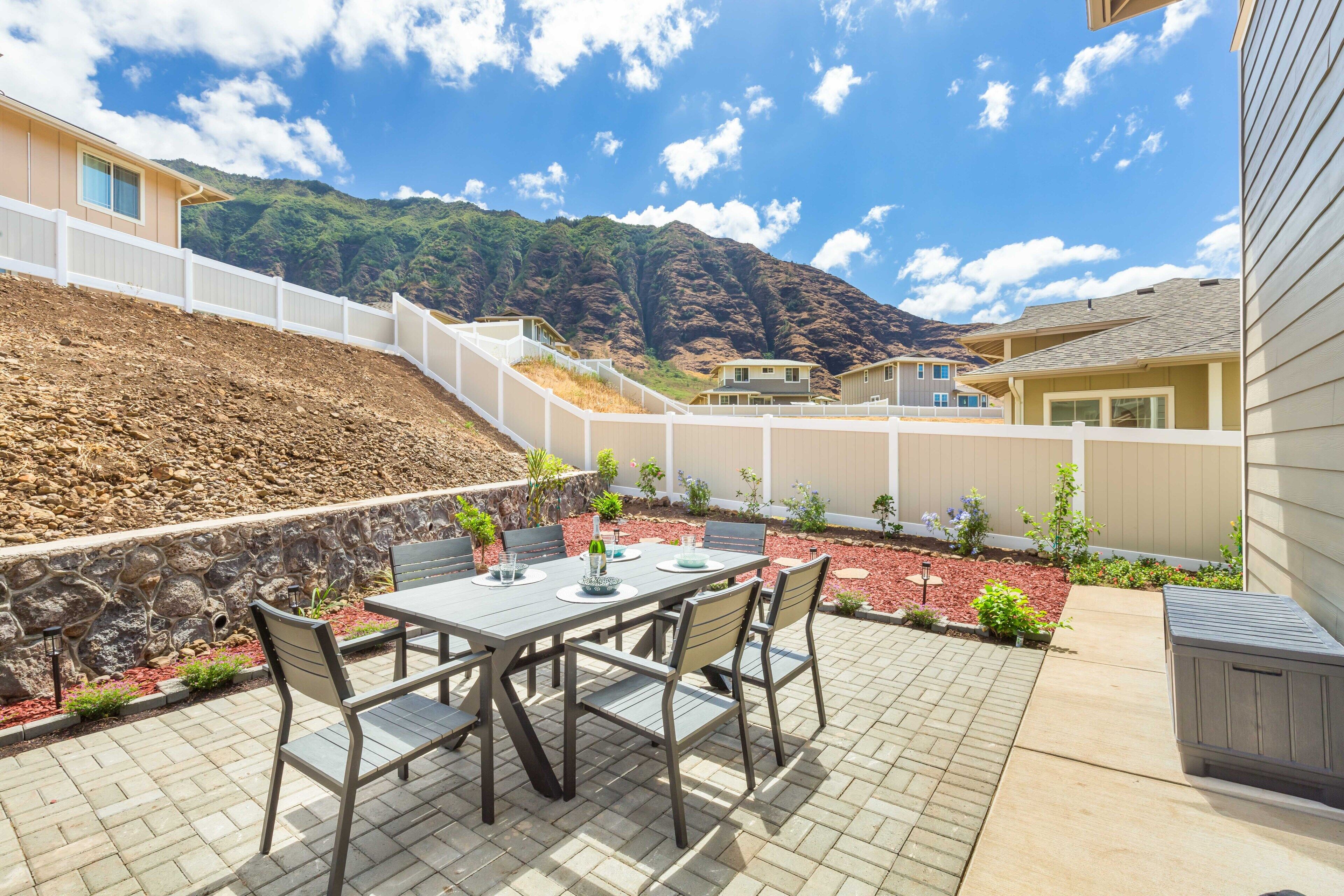 Un patio con una mesa y sillas, rodeado por un muro de piedra y vistas a la montaña.