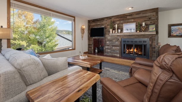 Una sala de estar con chimenea, un sofá y un sillón de cuero reclinable.