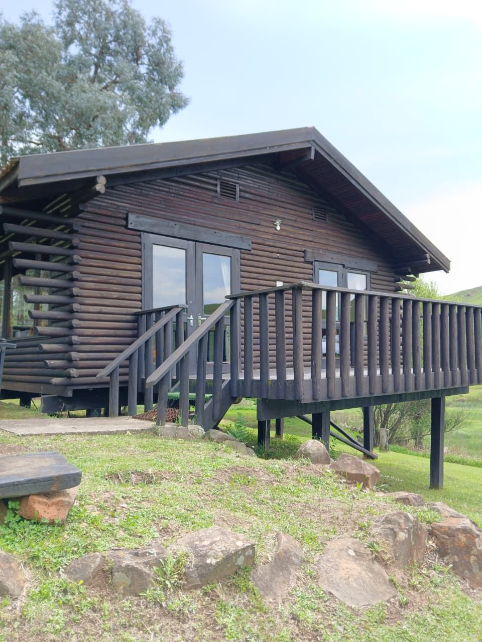A wooden cabin with a deck and stairs leading to the entrance.