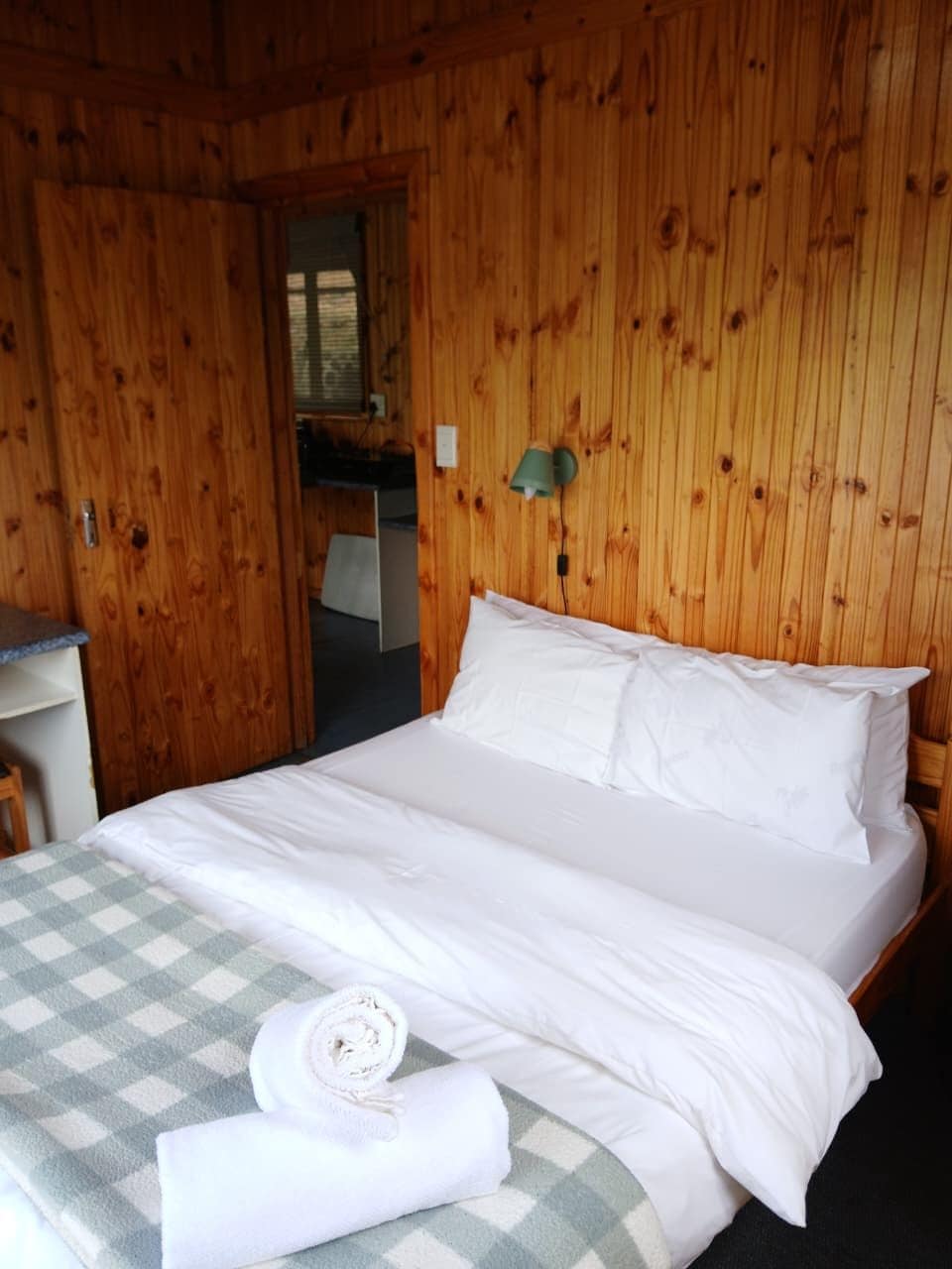 Una stanza con rivestimenti in legno, un letto, una scrivania e una lampada a parete.