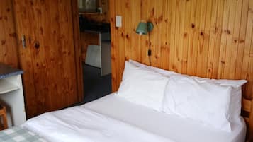 Una stanza con rivestimenti in legno, un letto, una scrivania e una lampada a parete.