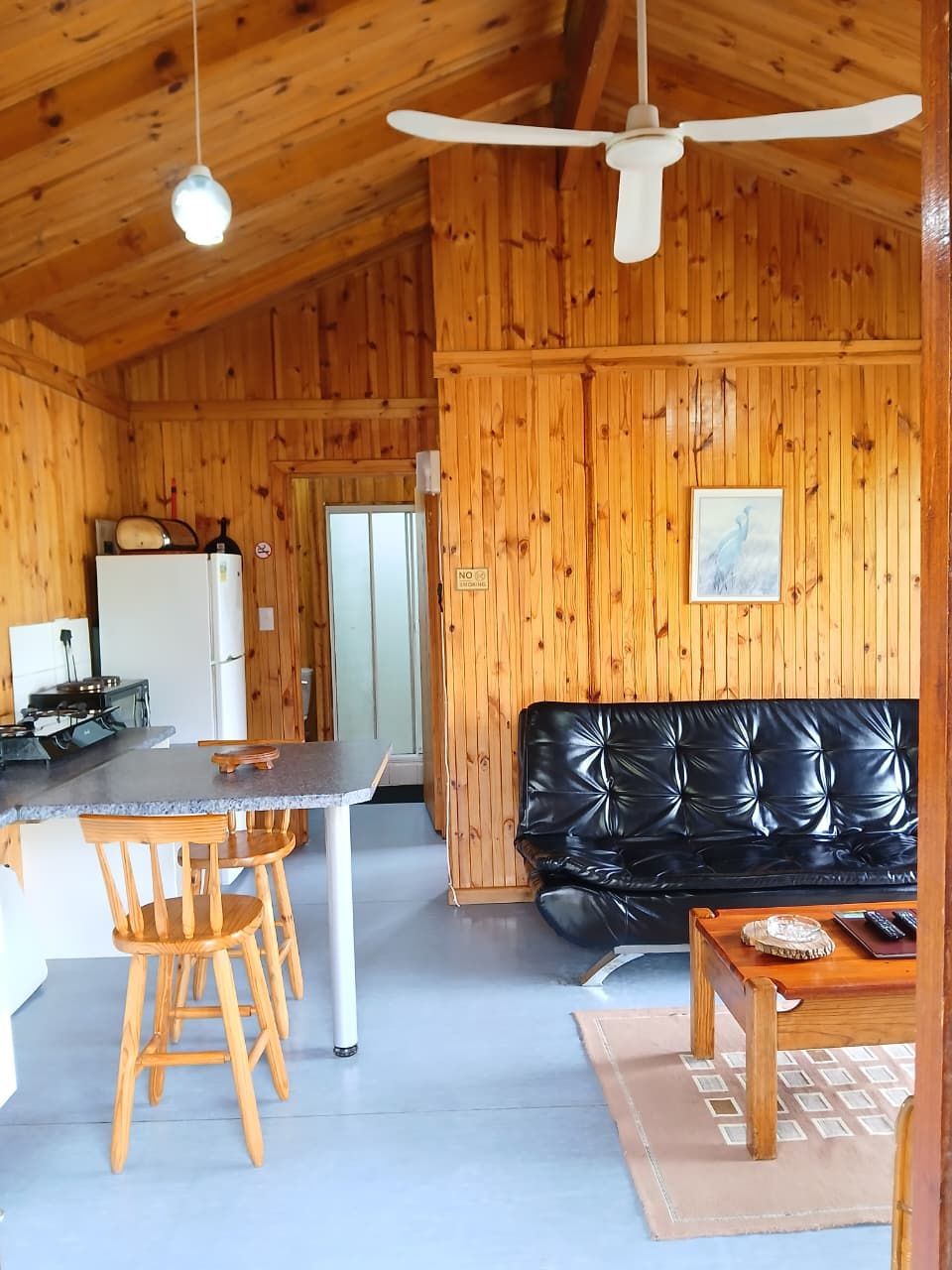 A cabin interior with a dining area, kitchen, and seating space.
