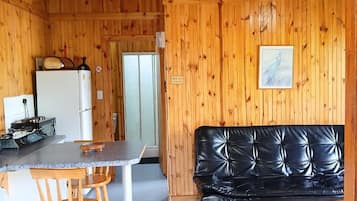A cabin interior with a dining area, kitchen, and seating space.