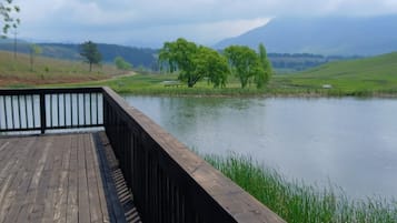 A wooden deck overlooking a calm lake with trees and hills in the distance.