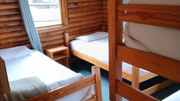 A cabin with two bunk beds, a small table, and a window with curtains.
