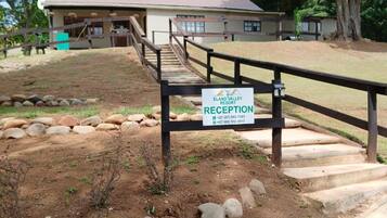 A reception area at Elan Valley Resort with a sign, a wooden fence, and a dirt path leading to a building.
