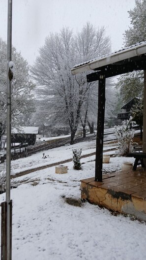Un espace extérieur enneigé avec un coin salon abrité et un chemin menant à un bâtiment.