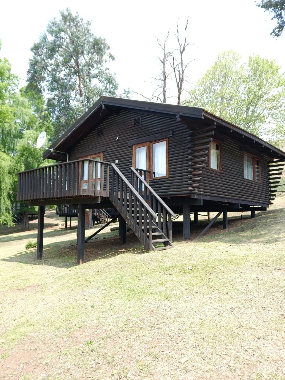 A log cabin with a deck and a staircase leading to the entrance.