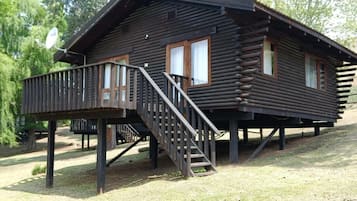 A log cabin with a deck and a staircase leading to the entrance.