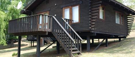 A log cabin with a deck and a staircase leading to the entrance.